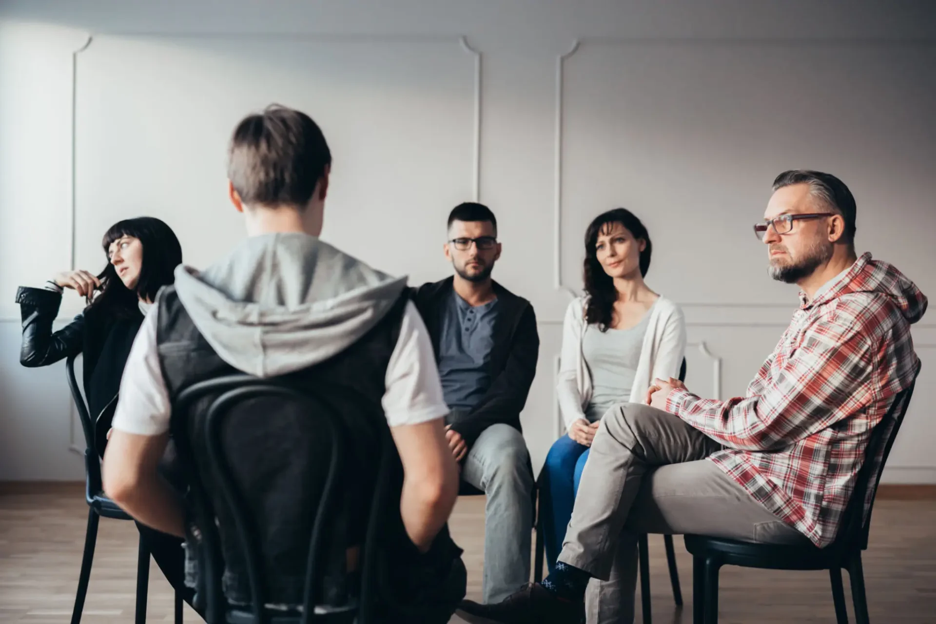 Individuals sit in chairs during a group counseling session.