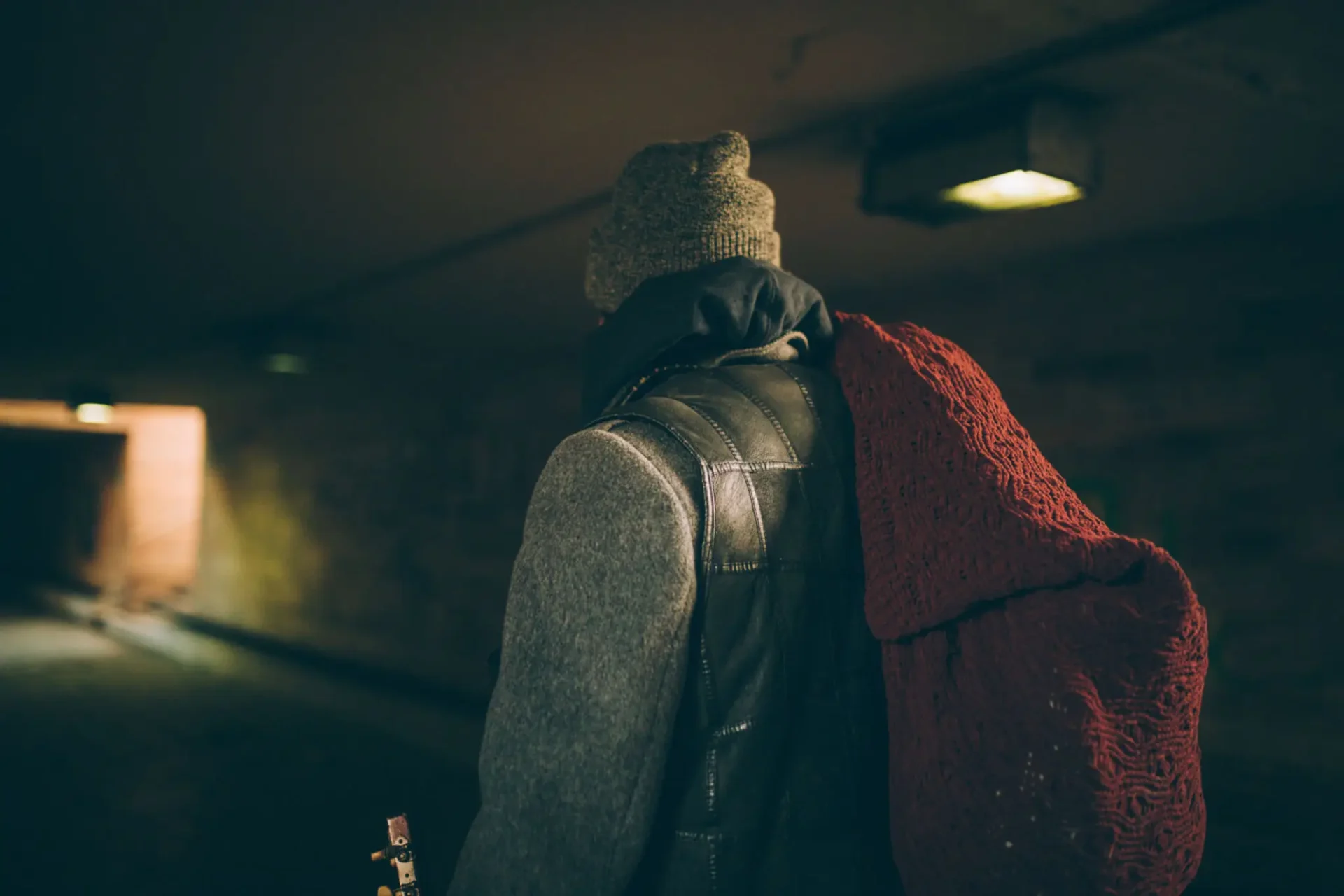 A person carrying a large sack walks through a tunnel.