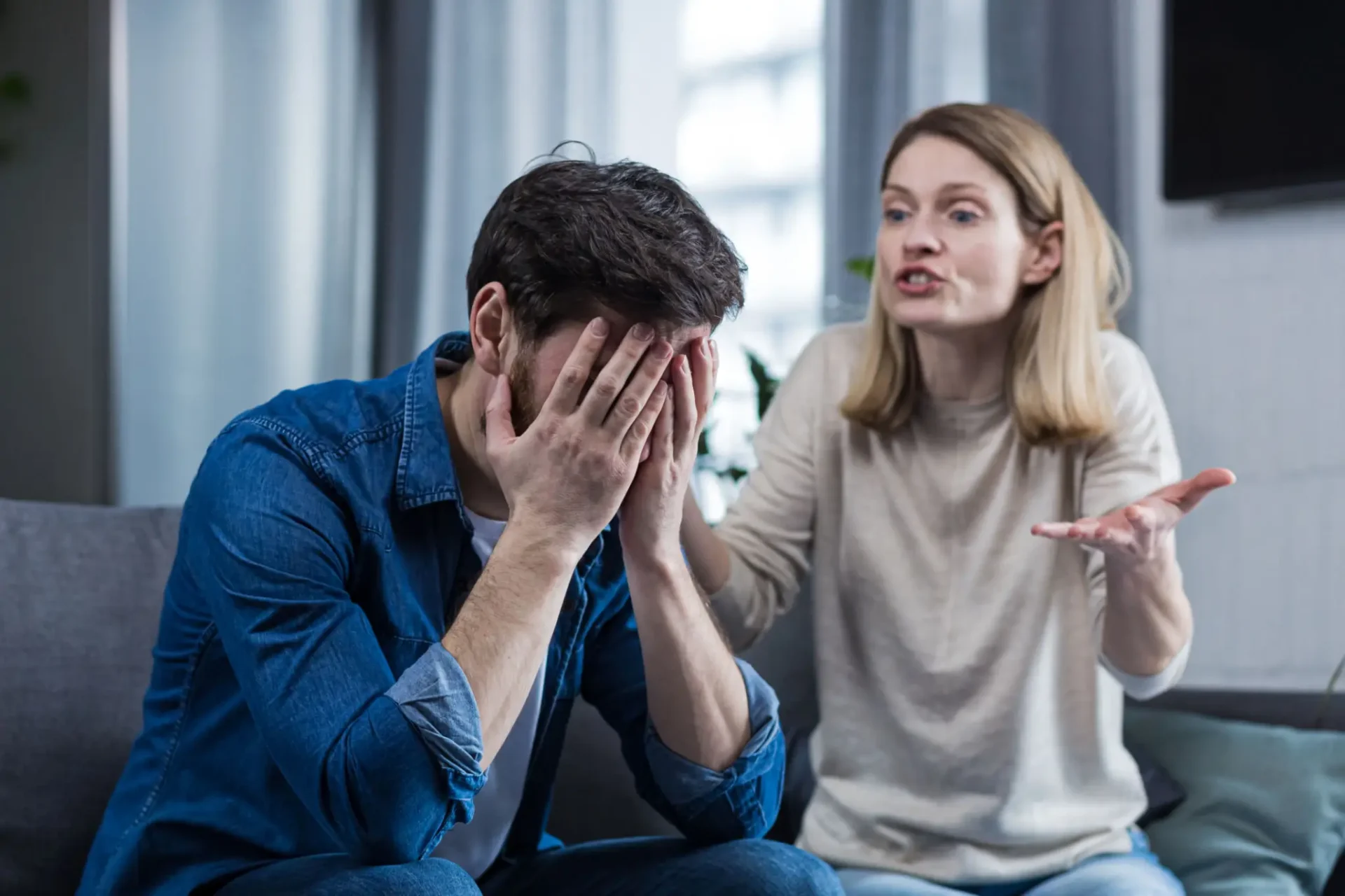 Man and woman sitting on a couch arguing.